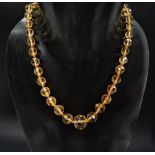 A possibly citrine graduated faceted bead necklace with gold clasp, the largest circular bead