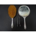 A silver hand mirror, together with a silver hairbrush and a pair of sugar tongs.