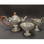 A George V silver three piece batchelor tea set of faceted pedestal form with crenallated edge,