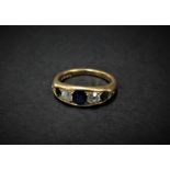 An 18ct. hallmarked gold diamond and sapphire five stone ring, the central oval sapphire measuring