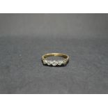 An 18ct. gold and platinum diamond set five stone ring, the larger central diamond of 0.05ct. spread