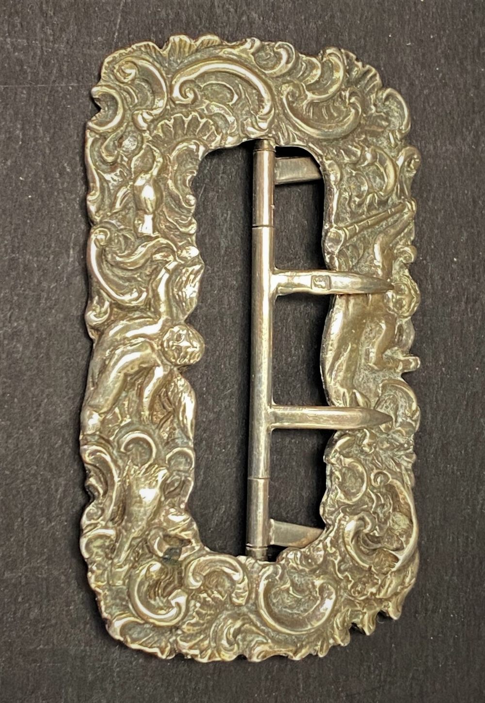 A Victorian silver cast buckle decorated with putti and foliate 'C' scrolls, maker G & M, London