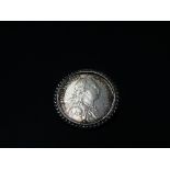 A George III 1787 shilling mounted brooch, the shilling within a swivel rope twist mount, weight