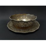 A Persian white metal foliate scroll pierced bowl and dish with foliate cast rims, stamped marks