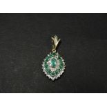 A modern 9ct. gold diamond and emerald cluster pendant, the central marquise cut emerald measuring