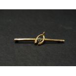 A 9ct. gold bar brooch applied with a wishbone and set with a blue stone, base metal pin, length