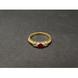 A modern 18ct hallmarked gold, diamond and ruby three stone ring, the central ruby of 0.25ct