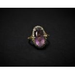 An 18ct. hallmarked gold amethyst and diamond cluster ring, the oval cut amethyst measuring 13.7 x