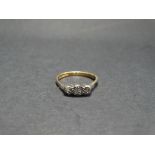 A 9ct. hallmarked gold diamond set three stone ring, the three small diamonds within an illusion