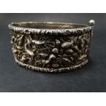 A Chinese silver heavy cast hinged bangle, with foliate cast edge and with a band of fish and