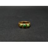 An 18ct. heavy gold three stone set gypsy ring, set with three green hardstones, stamped ct18,