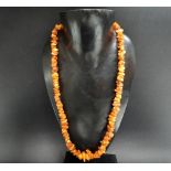 A raw butterscotch amber bead necklace with base metal clasp, length 64cm, weight 43.1g approx.