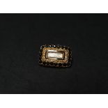 A George IV 18ct. gold mourning brooch set with black stones around a hair panel with black enamel