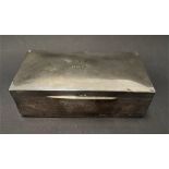 A silver hinge lidded cigarette box, the lid with engraved dedication, width 18cm (hallmarks