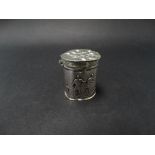 A continental white metal hinge lidded cylindrical box, the sides decorated with figures, the lid