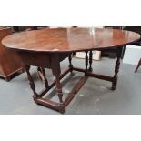 An 18th century oak drop leaf dining table fitted a single drawer above turned legs and plain