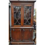 A mahogany bookcase cabinet in the Georgian style with astragal doors, dentil cornice and shell