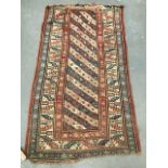 A middle eastern hand knotted wool rug with central rectangular panel with striped decoration and