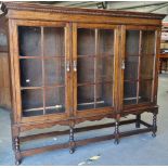 An English oak Jacobean style bookcase of three glazed doors above a barley twist framed base, width