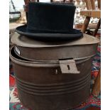 A moleskin top hat within a tin hat box.