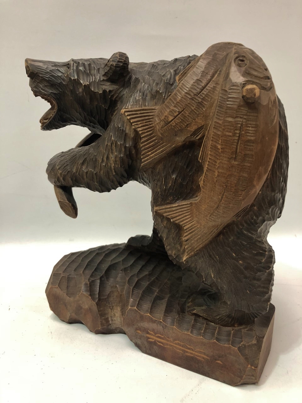 An oriental carved wood bear with two fish on his back, inscriptions to the back, height 36cm.