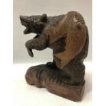 An oriental carved wood bear with two fish on his back, inscriptions to the back, height 36cm.