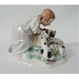 A Meissen porcelain group modelled as a girl in a nightdress looking over a basket with a litter