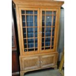 A 19th century pine glazed bookcase with astragal doors over blind doors, moulded pediment and
