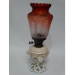 A pottery oil lamp base foliate encrusted with a orange blush glass etched shade, height 48cm.