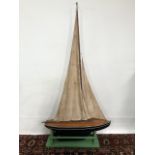 An early 20th century pond yacht with sails and upon stand, width of yacht 79cm, height 155cm.