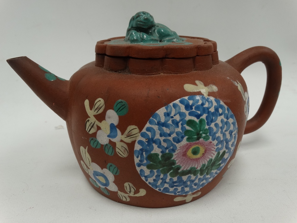 A Chinese Yixing teapot and cover of squat lobed ovoid form and decorated with foliate enamels,