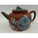 A Chinese Yixing teapot and cover of squat lobed ovoid form and decorated with foliate enamels,