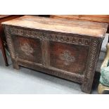 An 18th century oak coffer of typical form, the panelled front carved with circular decoration,