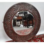 An English Arts & Crafts oak framed mirror fitted a bevelled plate, diameter 68cm.