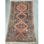 An eastern hand knotted wool rug, the centre with three lozenge medallions amongst foliage and