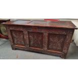 A late 18th century panelled oak English coffer, the front decorated with floral and leaf motifs,