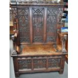 An unusual Victorian oak Gothic settle, the crenellated top rail over the three panel back with