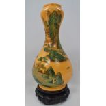 A Chinese gourd shaped yellow ground famille verte vase painted with a pagoda lake landscape, red