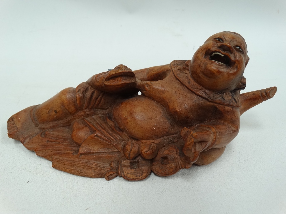 A Chinese root carving, carved as a jovial portly gentleman with a frog, with glass eyes and ivory