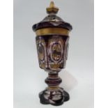 A bohemian amethyst overlay cut glass lidded pedestal vase with gilt and silvered enamel painted