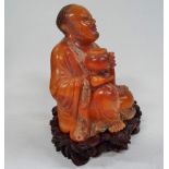 A Chinese Tianhuang carved figure of a seated lohan holding a censer, his robes foliate engraved and