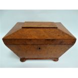 An early 19th century burr elm veneered tea caddy of sarcophagus form, hinged to reveal two lidded