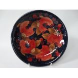 A Moorcroft pomegranate and grape design dish on a dark blue ground, signed and impressed marks to
