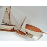 Three hand built wooden pond yachts by Charlie Trebilcock of Carnon Downs, the largest length 59cm.