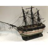 A 19th century naive painted wood model of a three masted ship on stand, length 26cm, height 63cm.