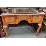 A walnut and crossbanded Queen Anne style dressing table fitted three drawers above shell capped