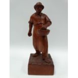 A continental carved wood sculpture of a farmer sowing seeds, the rectangular base monogrammed SL,