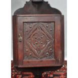 A small carved mahogany wall hanging corner cupboard with carved door, height 69.5cm.