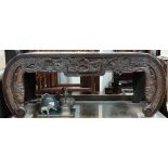 A Chinese hardwood carved coffee table with glazed top above a 'C' shaped profusely carved frame,