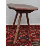 An early 18th century elm tripod table, the top of canted rectangular shape raised on three tapering